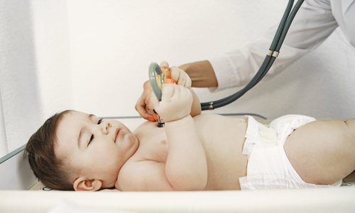 Doctor with stethoscope. Baby without clothes. Examination by a doctor.
